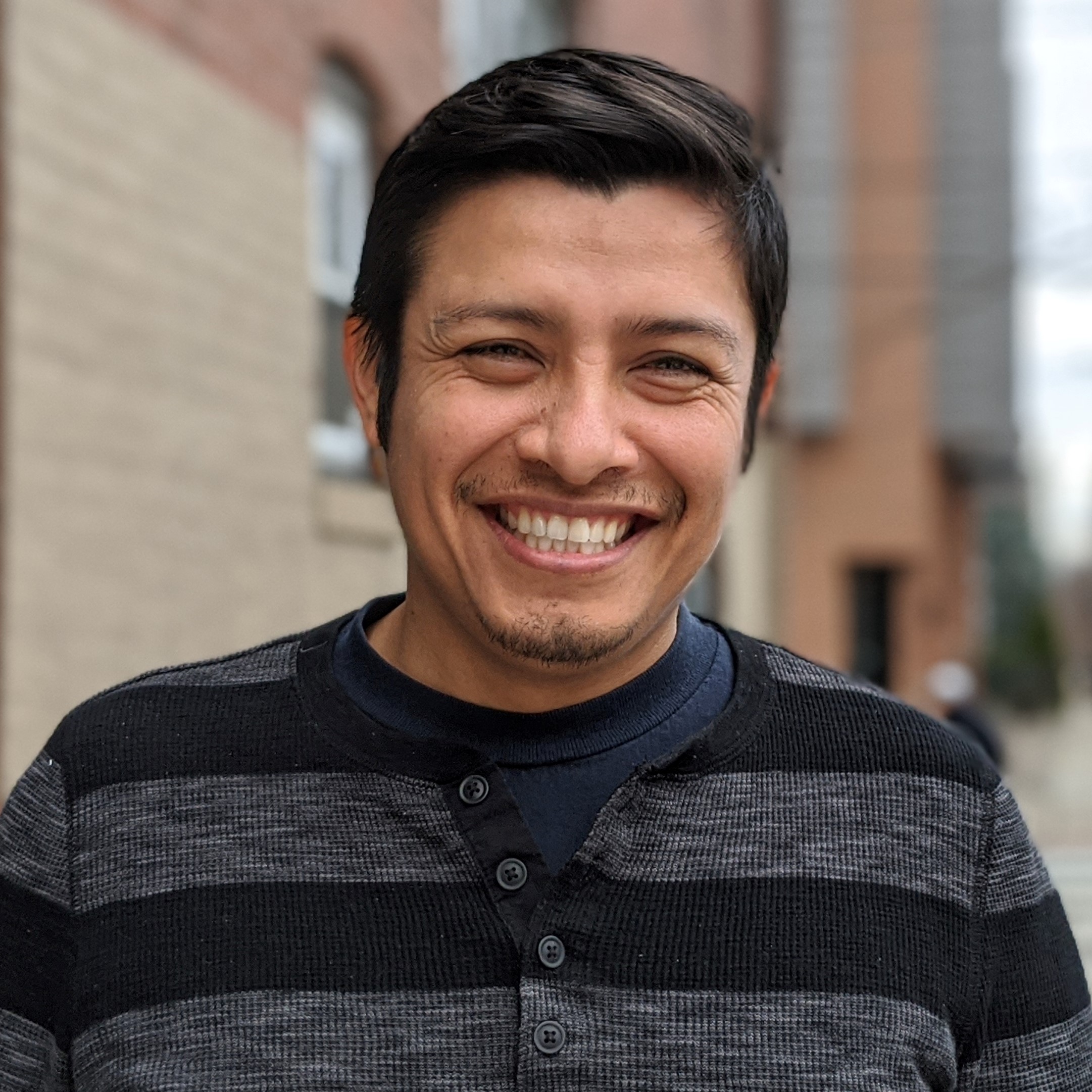 Portrait of smiling man with clean-cut short, dark hair and brown skin