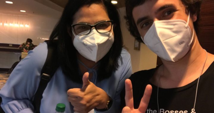 Denise Hernandez of Cooperative Home Care Associates takes a selfie with Michael Brennan, Special Projects Coordinator for the United States Federation for Worker Cooperatives. They both wear white surgical face masks and Michael flashes a peace sign.