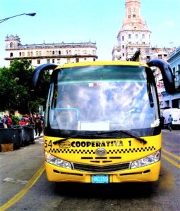 Front view of yellow bus in city street. Bus says "cooperativa 1" on it.
