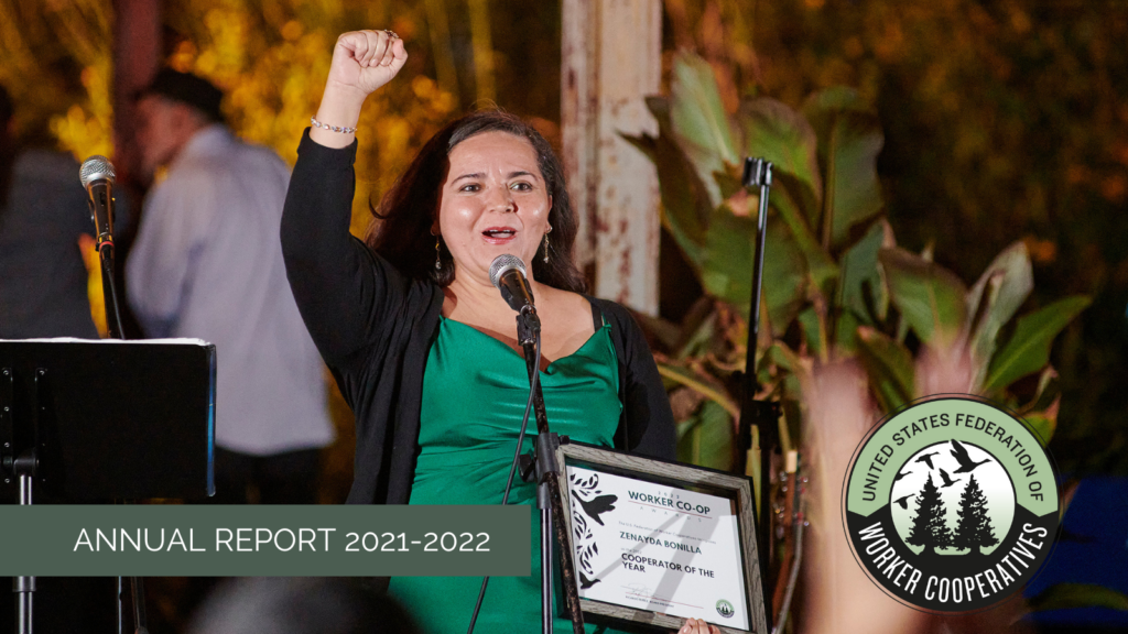 A photo of a woman with light skin, dark hair, wearing a black cardigan over a green gown, with a fist held high and holding a plaque that reads Zenayda Bonilla, worker cooperator of the year. Below the photo of Zenayda is the text Annual Report 2021-2022 and the logo of the USFWC.
