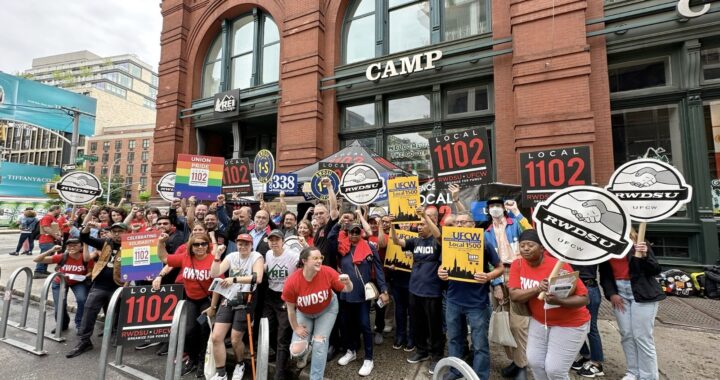 A group of people stand together with union signs in front of an REI store in New York City