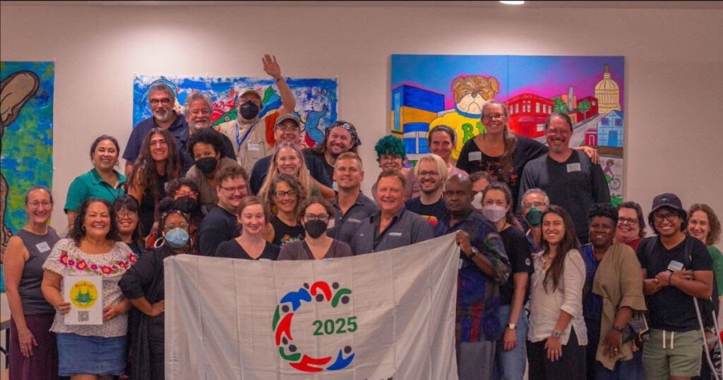 a group photo of around 40 people around a banner that says international year of the cooperatives, many smile and cheer