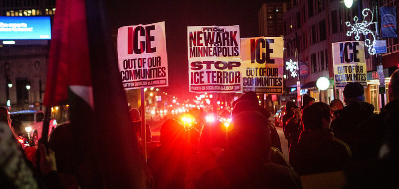 Protest posters that read from Newark to Minneapolis stop ICE terror and red police lights flashing