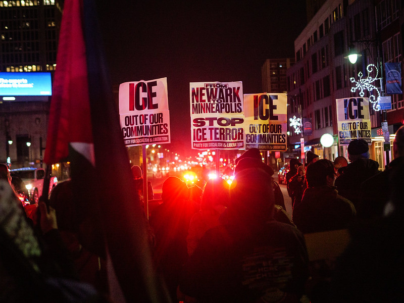 Protest posters that read from Newark to Minneapolis stop ICE terror and red police lights flashing