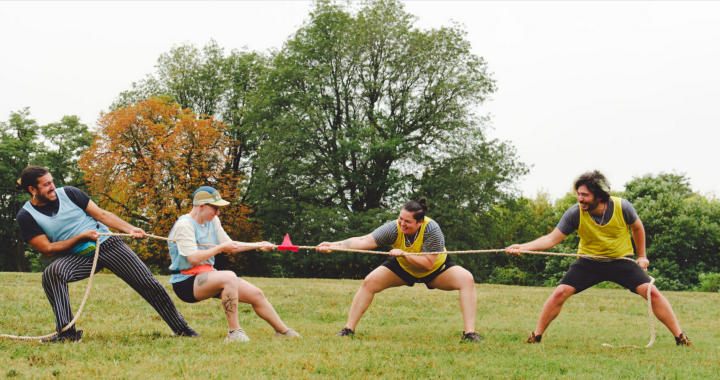 four people playing tug a war outside on the grass