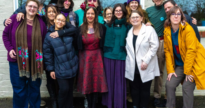 A photo of 14 people wearing winter clothes standing together and smiling.