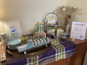 Una estacion de te con tazas para te y una variedad de tes sobre una mesa de madera. Un cartel dice Dandelion House