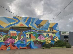 A colorful mural outside a concrete building with a sign that says fertile ground cooperative