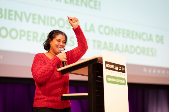 a person speaking through a microphone at a podium and gesturing 