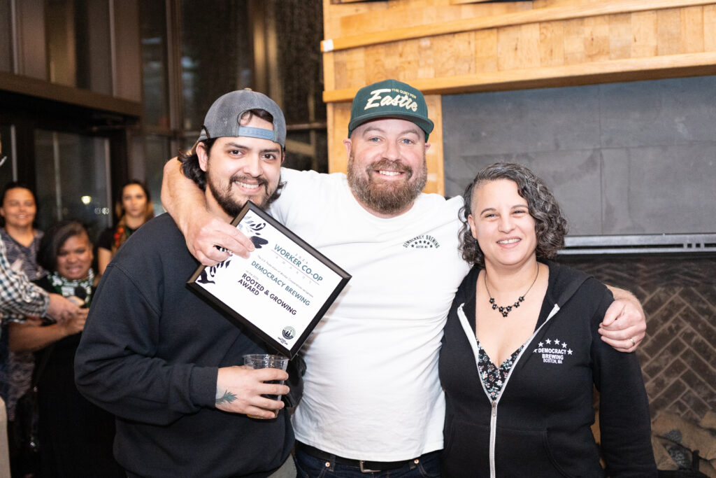 una foto de tres personas sonriendo y cargando un premio en la mano
