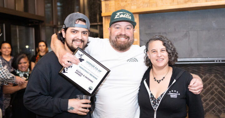 a photo of three people standing and smiling together holding an award plaque