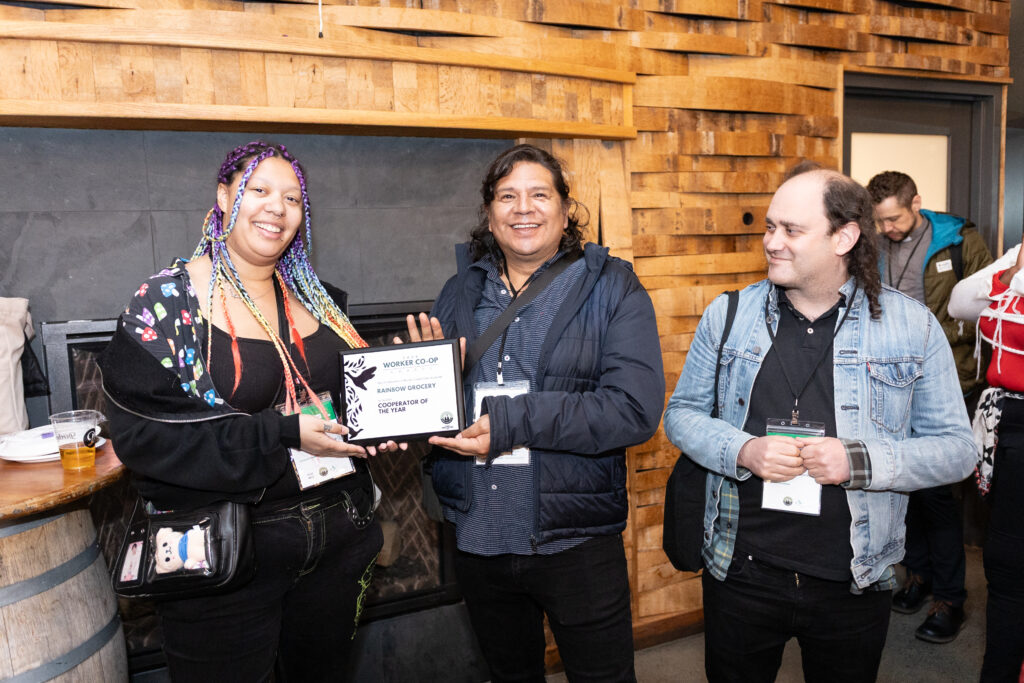 una foto de tres personas sonriendo y cargando un premio